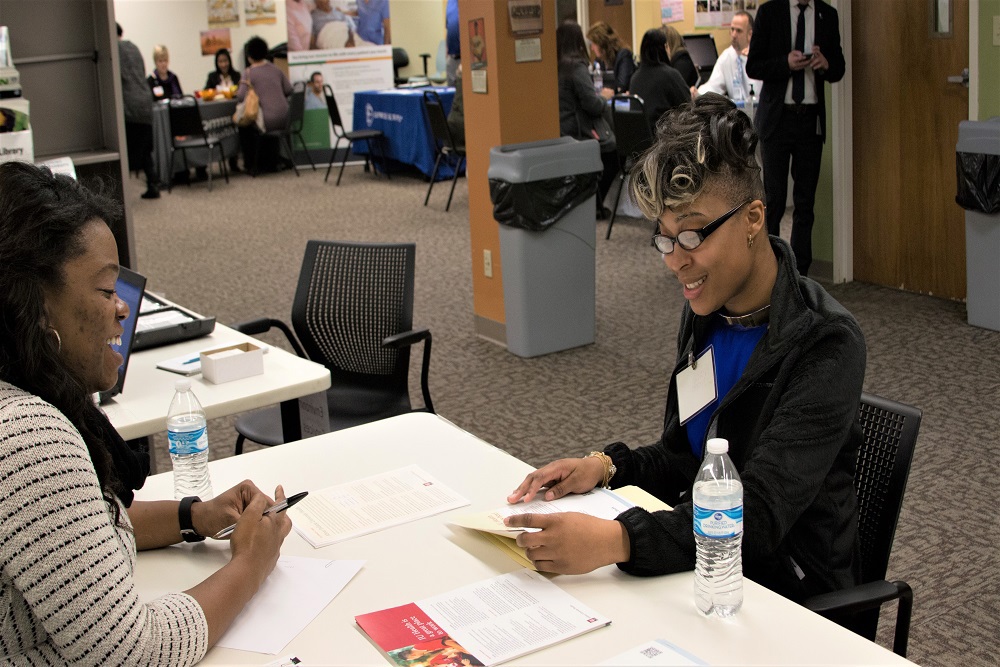 women sitting across from each other at table in a conference room