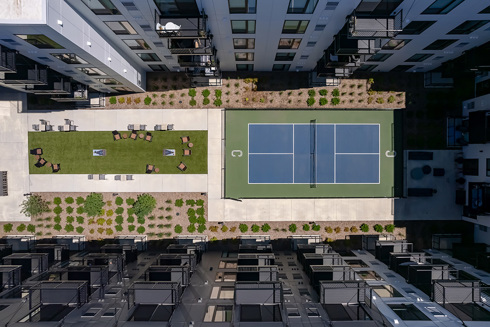 aerial view of multifamily development's outdoor amienity area with pickle ball court and dog run