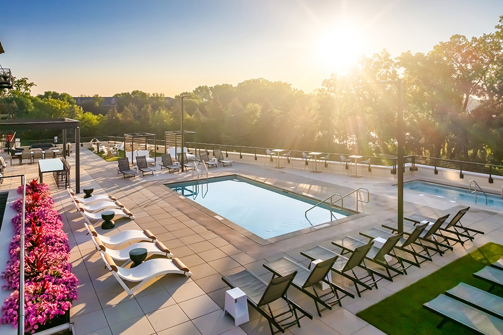 rooftop outdoor living area of an apartment building with swimming pool and deck chairs