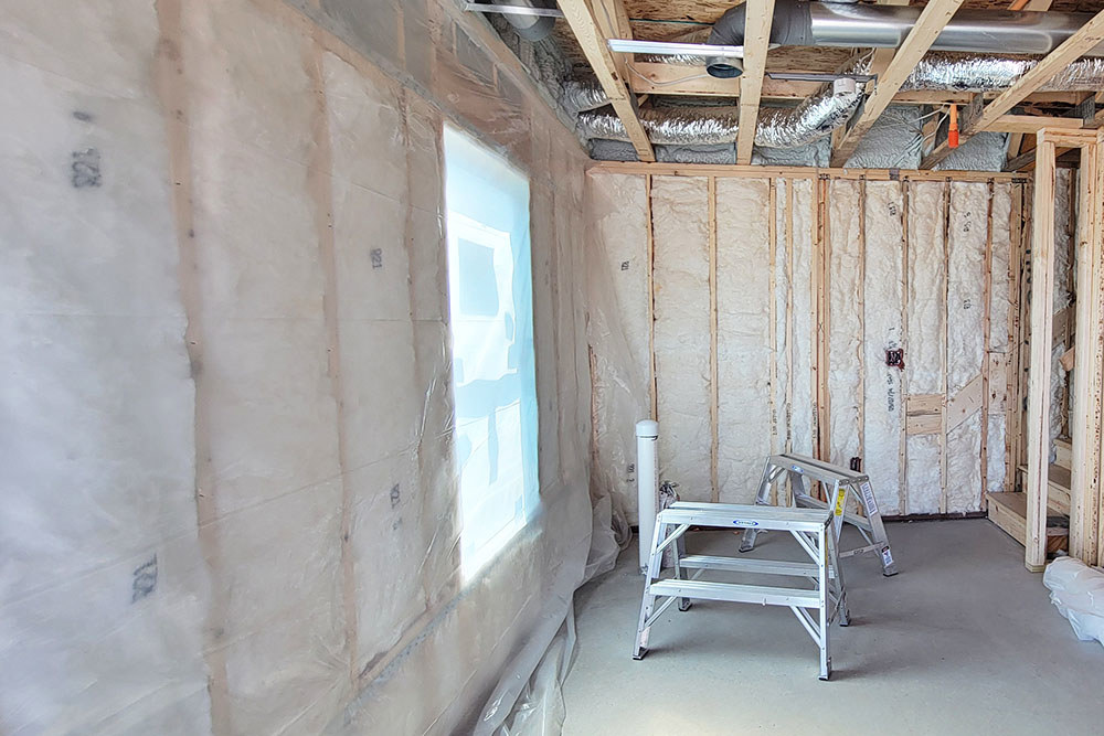 the room of a home under construction with the wood framing exposed and insulation installed