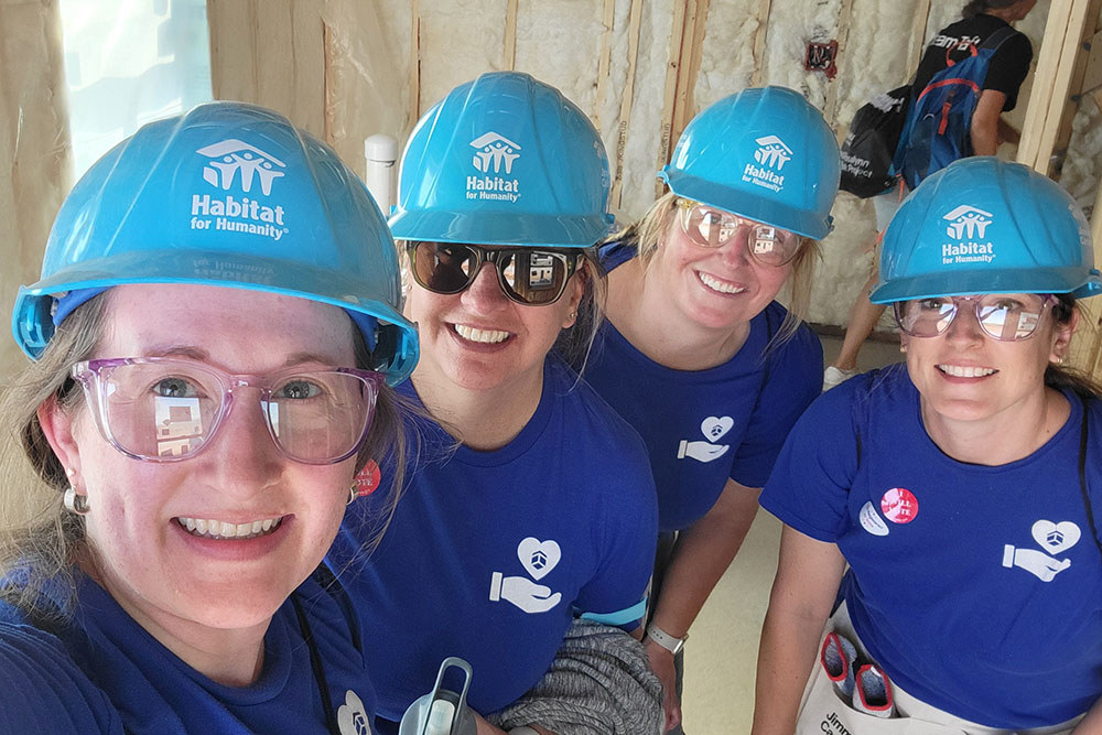 four women in matching shirts and hard hats pose for a group photo