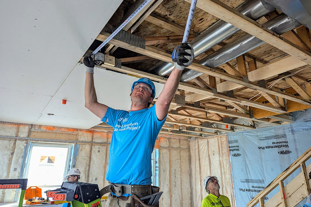 a man takes a measurement on the ceiling of a home under construction