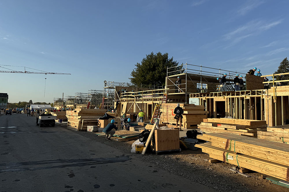 a long depth view of many homes under construction with exterior framing going up