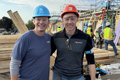 two smiling men wearing hard hats pose 