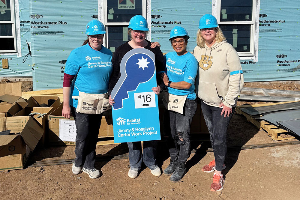 four women in matching shirts and hard hats pose for a group photo