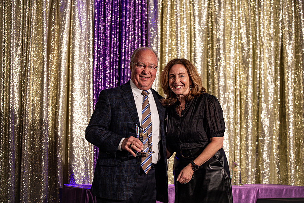 man and woman standing on a stage with man holding an award