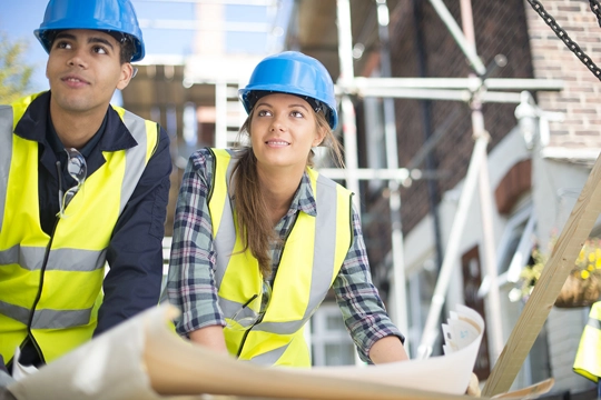 young man and woman wearing safety vests and hardhats