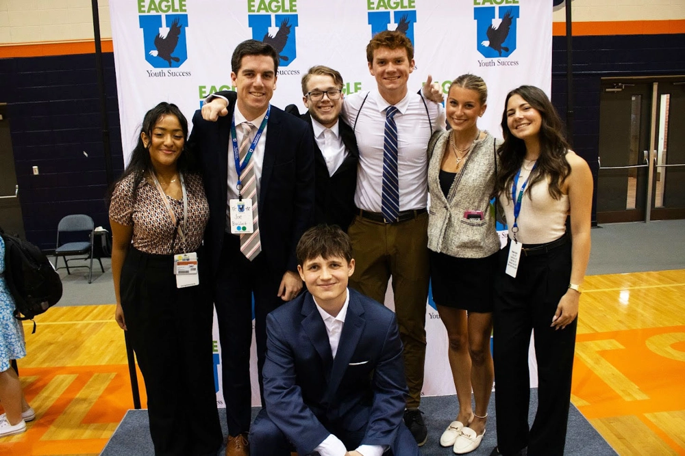 group of people in professional attire standing in front of blue and white backdrop