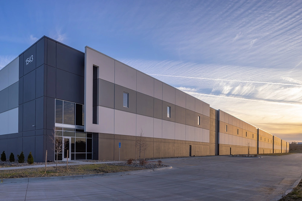 angled side view of the exterior of an industrial building at sunset with entrance in the foreground