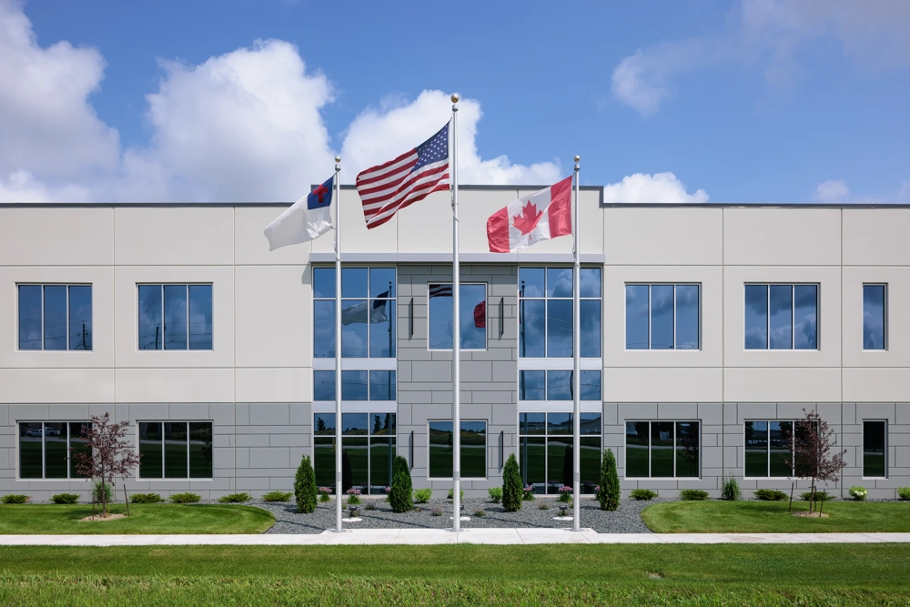 front glass entrance to a two-story building with three flags in the foreground