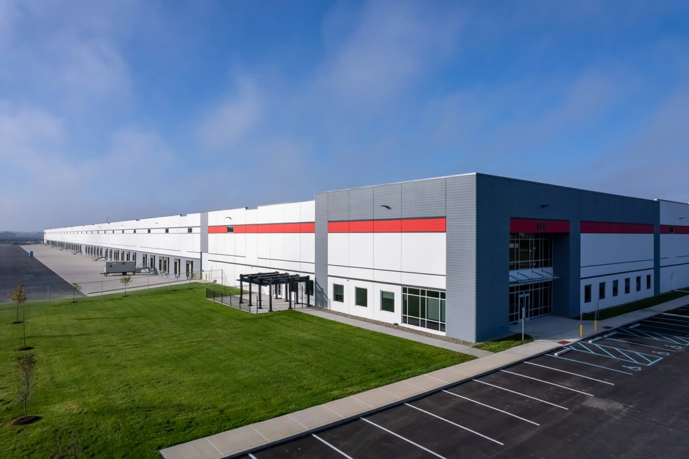 corner view of an industrial building with docks and landscaping on the left and entrance and parking lot on the right