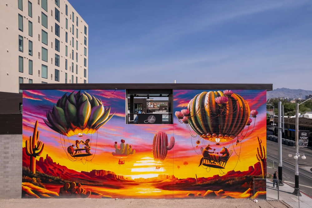 a large, vibrant outdoor mural on a building wall that shows multiple plant shaped hot air balloons rising above the ground at dusk