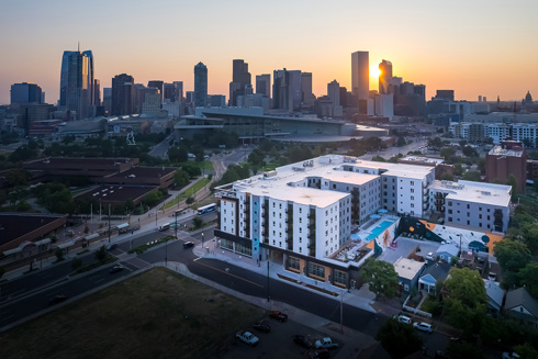 aerial view of multifamily development at sunset with Downtown skyline in background