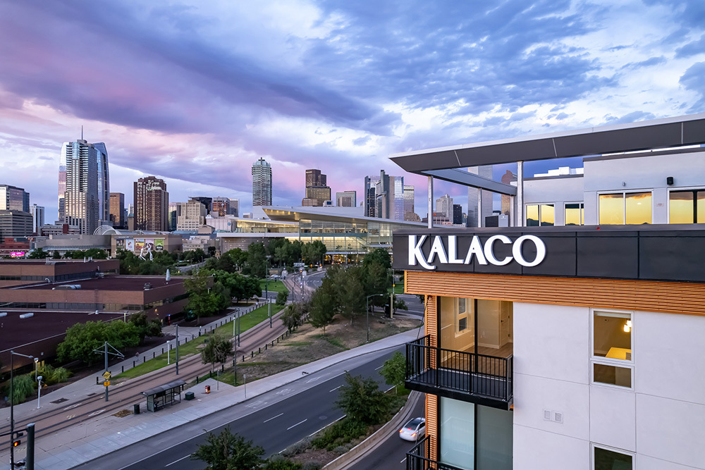 exterior of upper stories of multifamily development on right with Downtown skyline in background on left