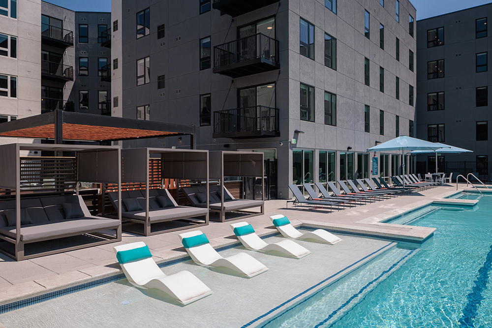 exterior of multifamily development with swimming pool in foreground and apartment towers in background