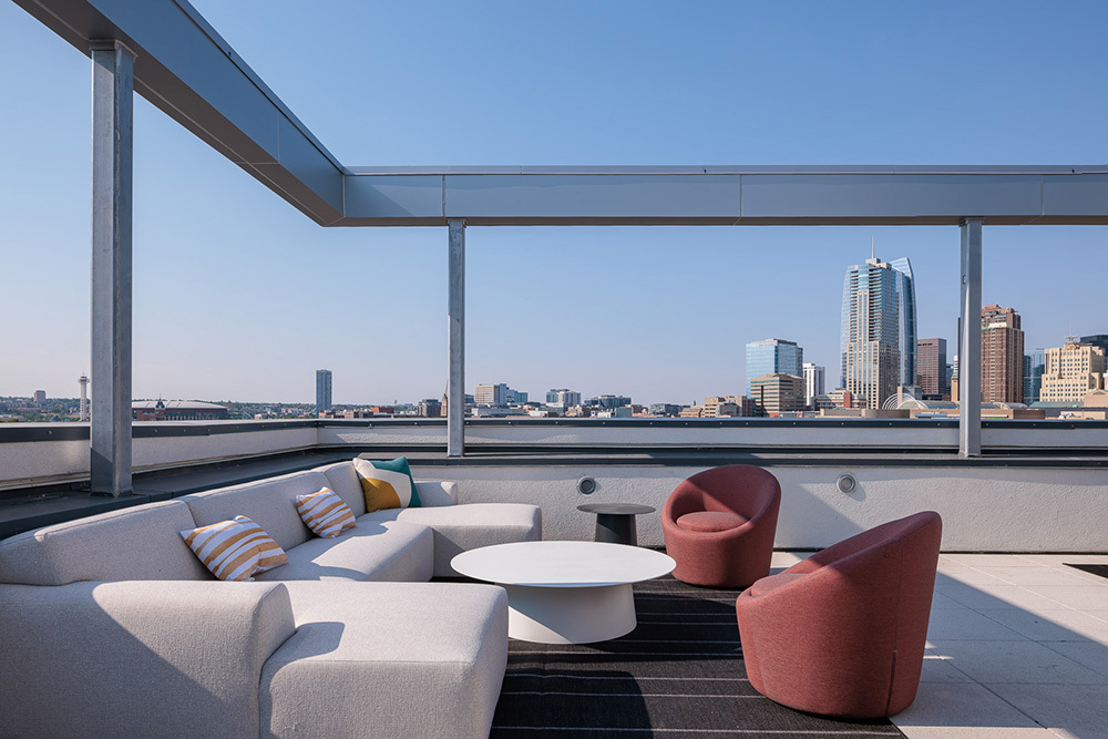 outdoor seating area on roof of multifamily development with Downtown skyline in background