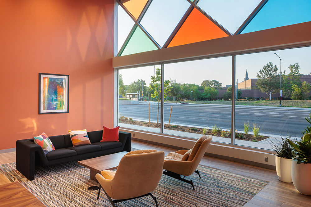 colorful seating area inside multifamily development with windows looking out onto the street