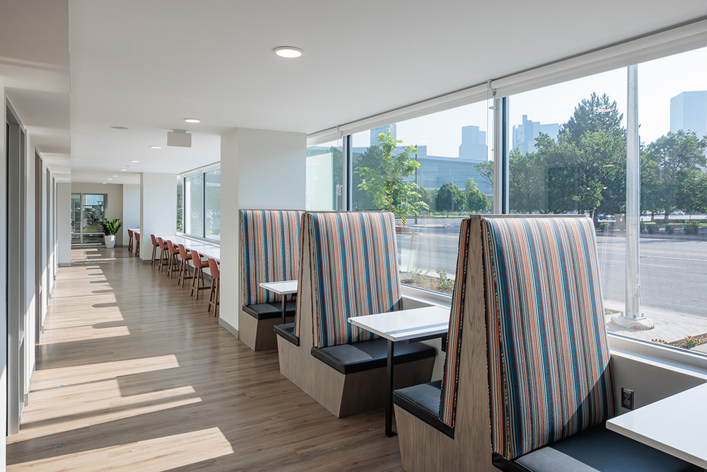 amienity area of multifamily development with row of booths with tables along a wall with windows