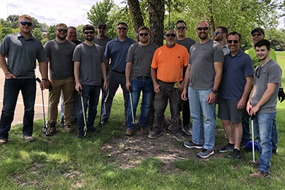 A group of people standing in rows in front of a tree.